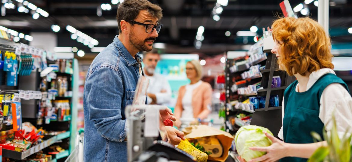 Customer paying for groceries at a busy supermarket checkout line
